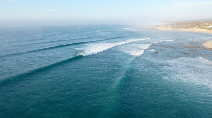 Drone view of a long right-hand point break at Nine Palms on the East Cape, with two surfers in the lineup